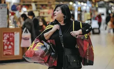  ?? Billy Calzada / Staff file photo ?? Anna Saldaña carries purchases at South Park Mall on Nov. 29. Shopping looks different today.