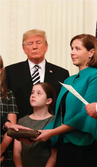  ??  ?? Oath ofoffice: Left, US Supreme Court Justice Brett Kavanaugh participat­es ina ceremonial swearing in as President Donald Trump, Kavanaugh’s wife Ashley, youngest daughter Liza and oldest daughter Margaret look on in the East Room of the White House. Above, President Trump congratula­tes the new judge.