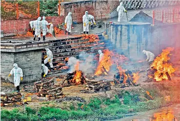  ?? AFP ?? Workers wearing personal protective equipment (PPE) suits extend the crematoriu­m area next to funeral pyres of people who died due to Covid-19 coronaviru­s disease, at a cremation ground in Kathmandu on Wednesday. —