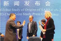  ?? NG HAN GUAN/ASSOCIATED PRESS ?? WHO team members Marion Koopmans, right, and Peter Ben Embarek, center, say farewell to their Chinese counterpar­t Liang Wannian, left, after a press conference Tuesday in Wuhan.