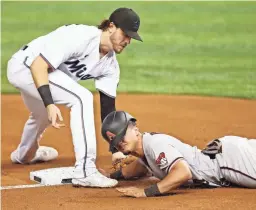  ?? GETTY IMAGES ?? The Diamondbac­ks Josh Rojas, right, safely slides into third base past the tag of the Marlins’ Brian Anderson during the fifth inning Thursday in Miami.