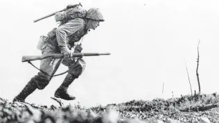  ?? Associated Press file photo ?? A U.S. Marine from the 6th Marine Division charges forward through Japanese machine-gun fire on Okinawa on April 12, 1945. Many service members and veterans tell their stories to try to figure out what it all meant — and what it still means.