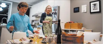  ?? Carolyn Kaster The Associated Press ?? Sen. Kirsten Gillibrand, D-N.Y., and her son Henry Gillibrand set the table for dinner Tuesday in their home in Washington. Gillibrand isn’t just embracing her role as a mother on the campaign trail, she’s running on it.