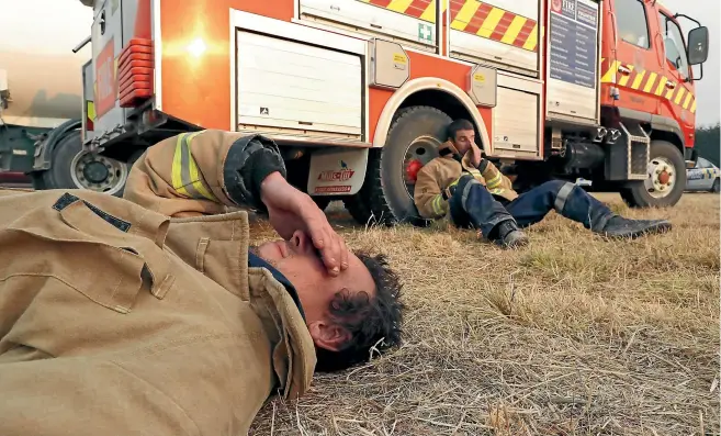  ?? MARTIN DE RUYTER/ STUFF ?? Takaka volunteer firefighte­rs Callum Reid, front, and Grant Lawrence show the fatigue of fighting the outof-control fire.