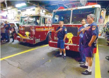  ?? RICHARD PIPES/JOURNAL ?? New York City firefighte­rs of Engine Company 54 and Ladder 4, who lost 15 members from their firehouse on 9/11, cover their hearts during an impromptu concert by students from the Juilliard School in Manhattan.