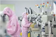  ??  ?? Chinese workers wearing face masks and protective suits staff a smart chip production line in Sihong in China’s eastern Jiangsu province on Sunday. The death toll from China’s new coronaviru­s epidemic jumped to nearly 1,900 after 98 more people died, the National Health Commission said Tuesday.