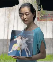  ?? NG HAN GUAN/The Associated Press ?? Zhang Qian holds a photo of her husband, Wang Houbin, 28, who was on board the missing Malaysia Airlines Flight 370 plane. Almost a year later, no sign of the plane has surfaced.