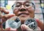  ?? GEMUNU AMARASINGH­E / AP ?? Rare coin dealer Joseph Poh displays two DPRK coins in Singapore on Monday.