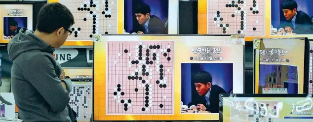  ?? (foto di Ahn Young-joon/Ap) ?? In diretta tv Un residente di Seul guarda sullo schermo la sfida tra il campione di Go Lee Sedol e AlphaGo, il software di Alphabet, durante il «Google DeepMind Challenge Match»