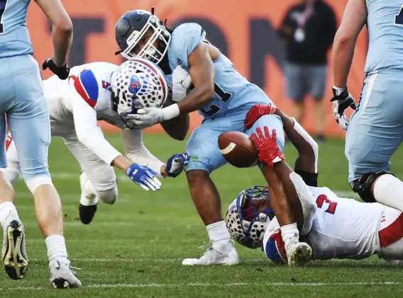  ?? Andy Cross, The Denver Post ?? Cherry Creek’s Tyler Tolbert, left, forces a fumble by Valor Christian’s Gavin Sawchuk, middle, in the first quarter of the Class 5A state championsh­ip at Empower Field on Saturday. Cherry Creek’s Logan Brantley, right, was in on the play.