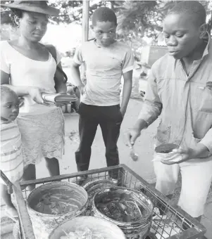  ??  ?? Mr Farai Sibanda (right) sells a tin of black floor polish for $20 to a client at Bulawayo’s Central Business District on Thursday. He manufactur­ers a variety of floor polishes