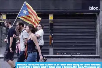  ??  ?? BARCELONA: This file photo taken on October 03, 2017 shows people walking past a closed store during a general strike in Catalonia called by Catalan unions in Barcelona. More than 2,700 companies have moved their headquarte­rs out of Catalonia and the...