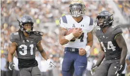  ?? PHELAN M. EBENHACK/AP ?? Navy fullback Mike Martin (34) rushes for a 14-yard touchdown between Central Florida defensive back Aaron Robinson, left, and linebacker Nate Evans during the second half Saturday, in Orlando, Fla.