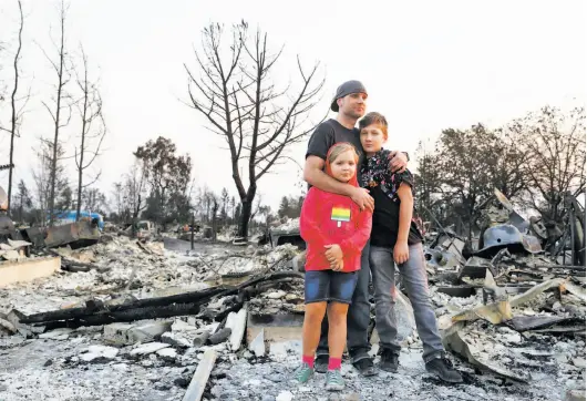  ?? Lea Suzuki / The Chronicle ?? Jimmie Allen (center) stands with his children Miley Allen (left), 9, and Jaden Frank, 13, on the ashes that were their home in Coffey Park in Napa.