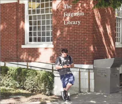  ?? Tyler Sizemore / Hearst Connecticu­t Media ?? Stamford's Rion Baptist browses on his phone outside the Ferguson Library in Stamford on Sunday. Thanks to the Connecticu­t Education Network, the Ferguson Library Downtown branch, Weed branch, and Harry Bennett branch will all have stronger and more reliable Wi-Fi outside of the building, which the library hopes will help bridge the digital divide.