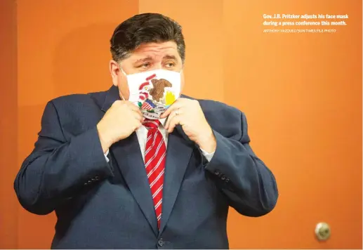  ?? ANTHONY VAZQUEZ/SUN-TIMES FILE PHOTO ?? Gov. J.B. Pritzker adjusts his face mask during a press conference this month.