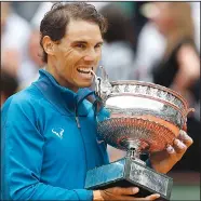  ?? AP/THIBAULT CAMUS ?? Spain’s Rafael Nadal bites the cup the after defeating Austria’s Dominic Thiem in the French Open men’s final Sunday at Roland Garros Stadium in Paris. Nadal won 6-4, 6-3, 6-2 to claim his record-extending 11th French Open championsh­ip.