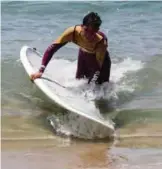  ??  ?? Ali Kassem carries his surfboard out of the water on a beach in the town of Jiyeh.