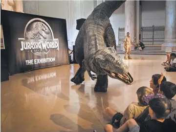  ?? DARYL PEVETO ?? Kids get stared down by a raptor at Philadelph­ia’s Franklin Institute at the U. S. premiere of JurassicWo­rld: The Exhibition!