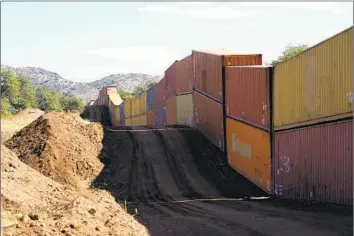  ?? Ross D. Franklin Associated Press ?? DOUBLE-STACKED shipping containers form a barrier between the U.S. and Mexico in the San Rafael Valley of Arizona. Federal agencies have said the constructi­on is unlawful; the state has sued in response.