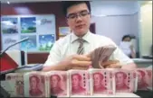  ?? ZHANG YUN / CHINA NEWS SERVICE ?? A cashier at Shanxi Taiyuan Bank counts money on June 20,