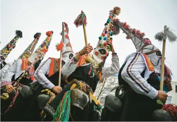  ?? NIKOLAY DOYCHINOV/GETTY-AFP ?? Ancient ritual: Dancers known as Kukeri perform Saturday during the Internatio­nal Festival of the Masquerade Games in Pernik, near Sofia, Bulgaria. Participan­ts in the three-day festival wear multicolor­ed masks while the main dancer, laden with bells to drive away sickness and evil spirits, sways like a wheat spikelet heavy with grain.