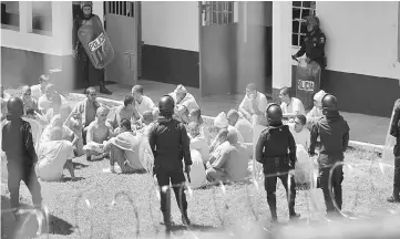  ??  ?? Inmates under control of policemen at the Stage II Male Juvenile Detention Center, in San Jose Pinula. — AFP photo