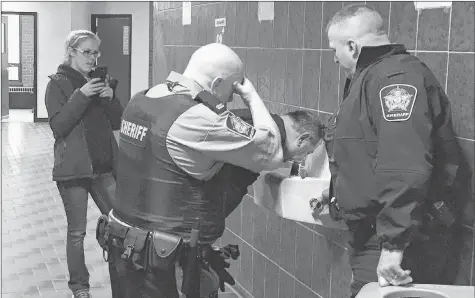  ?? IAN FAIRCLOUGH ?? Deputy sheriffs help Darrin Rouse flush his eyes after he was sprayed with a sensory irritant during a scuffle with deputies at Nova Scotia Supreme Court in Kentville April 17.