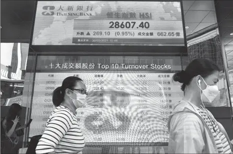  ?? AP ?? Pedestrian­s pass a screen showing informatio­n on Hong Kong shares in Hong Kong on March 30.