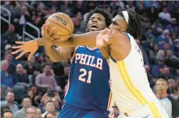  ?? JEFF CHIU/AP ?? Philadelph­ia 76ers center Joel Embiid is fouled by Golden State Warriors forward Kevon Looney while driving to the basket during the first half of Friday’s game in San Francisco.