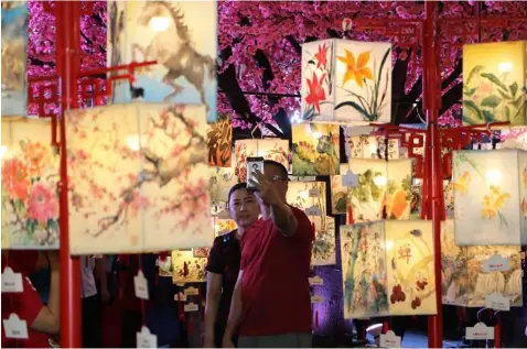  ?? -Chris Navarro ?? ART LANTERNS. Shoppers view the different designs and colors of hand painted lanterns during Sunday’s 36th Chan Lim exhibit at SM City Clark.