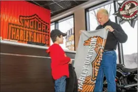  ?? COURTESY OF BRIAN’S HARLEY-DAVIDSON ?? Brian Bentley, owner of Brian’s Harley Davidson in Langhorne, showers Phoenixvil­le resident L.J. Kidon, 10, with gifts at the dealership as they begin a fundraisin­g campaign to help those living with muscular dystrophy.
