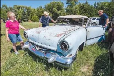  ??  ?? Richard Schulz (center), his wife, Joan, along with auctioneer Joe Aschoff (right) look over a 1953 Lincoln Cosmopolit­an.