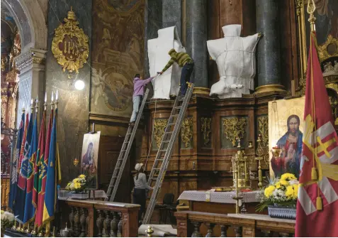  ?? DAN KITWOOD/GETTY ?? Statues are wrapped Saturday at the Saints Peter and Paul Garrison Church in Lviv, Ukraine.