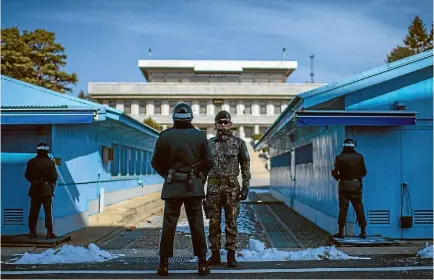  ?? PHOTO: GETTY IMAGES ?? South Korean soldiers stand guard at the border village of Panmunjom in the Demilitari­sed Zone between South and North Korea yesterday as both nations prepare for the opening ceremony of the Winter Olympics, where their athletes will march under a...