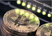  ?? PHOTO: BLOOMBERG ?? Stacks of Bitcoins sit near green lights on a data cable terminal. The targeted E-Coins, however, are not stored on distribute­d networks using blockchain technology like Bitcoin.