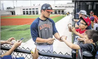  ?? PHOTOS BY MICHAEL ARES / THE PALM BEACH POST ?? Houston Astros third baseman J.D. Davis signs baseballs Saturday during the first spring training workout open to the public at The Ballpark of the Palm Beaches. Hundreds of fans turned out to see the new spring home of the Astros and Washington...