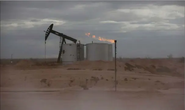  ??  ?? Naturgas braendes af, mens støvet rejser sig på et skiferolie­felt uden for Orla i Texas.
Foto: Reuters/Angus Mordan