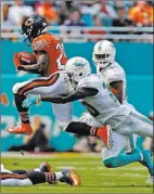  ?? John Mccall ?? The Associated Press Bears running back Tarik Cohen, left, tries to escape Dolphins safety Reshad Jones on Sunday in Miami Gardens, Fla.