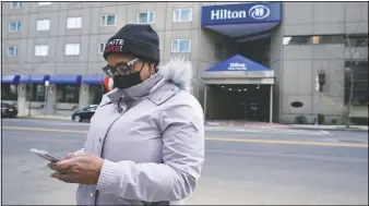  ?? (AP/Charles Krupa) ?? Hotel housekeepe­r Esther Montanez looks at her cellphone outside the Hilton Back Bay in Boston. Montanez refuses to give up hope of returning to her cleaning job at the hotel, which she held for six years until being furloughed since March 2020 due to the covid-19 virus outbreak. The single mother cannot bear the idea of searching for work that will almost certainly mean earning near the minimum wage.