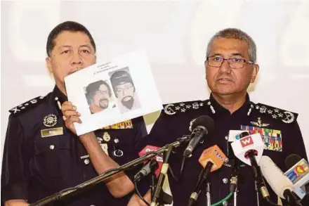  ?? PIX BY AIZUDDIN SAAD ?? Inspector-General of Police Tan Sri Mohamad Fuzi Harun (right) showing the image of one of the suspects at the police headquarte­rs in Bukit Aman, Kuala Lumpur, yesterday.