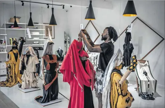  ?? Photos: Luis TATO/AFP ?? Garment-maker: Rwandan fashion designer Moise Turahirwa works on a piece for the new collection at their studio in Kigali.