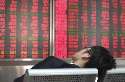  ?? AFP PHOTO ?? A man rests in front of boards showing stock prices at a securities company on the first trading day of the year in Beijing on January 2, 2018.