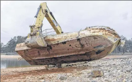  ?? DAVID BARNES PHOTOS / CONTRIBUTE­D ?? An abandoned houseboat is lifted onto a tow truck after being dragged away from Lake Lanier and demolished in Cumming on Monday. After being declared debris, the Lake Lanier Associatio­n was able to remove the abandoned houseboat, which is the third...