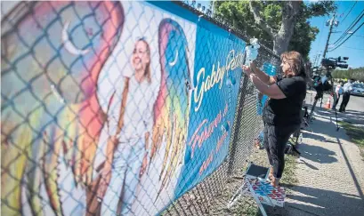  ?? EDUARDO MUNOZ AVAREZ THE ASSOCIATED PRESS ?? A woman places decoration­s near a poster after attending the funeral service of Gabby Petito at Moloney's Funeral Home in Holbrook, N.Y., on Sunday. Petito’s body was discovered last Sunday in a remote area in northweste­rn Wyoming.