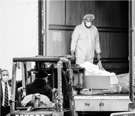  ?? AP ?? A body wrapped in plastic is loaded onto a refrigerat­ed container truck used as a temporary morgue by medical workers wearing personal protective equipment due to COVID-19 concerns last week at Brooklyn Hospital Center in the Brooklyn borough of New York.