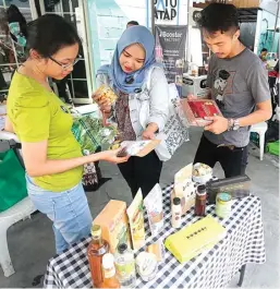 ?? GALIH COKRO/JAWA POS ?? SEGAR-SEHAT: Salah satu peserta bazar, Tarita Sandra (kiri), menerangka­n produk yang dijual kepada pengunjung di co-working space Satu Atap kemarin.