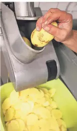  ??  ?? Die gewaschene­n und geschälten Kartoffeln werden auf eine einheitlic­he Dicke geschnitte­n.