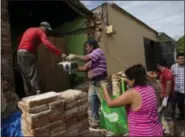  ?? REBECCA BLACKWELL — THE ASSOCIATED PRESS ?? Men pass a boom box out to Rosa Elia Cruz, 43, as they help her family salvage household goods and reusable bricks from their home destroyed in Thursday’s magnitude 8.1 earthquake, in Union Hidalgo, Oaxaca state, Mexico, Sunday.