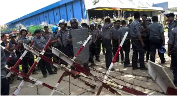  ?? — AFP photo ?? Police personnel stand guard along a street near the Chinese-owned Fu Yuen Garment factory after armed thugs beat up and hospitalis­ed some workers on strike, on the outskirts of Yangon.